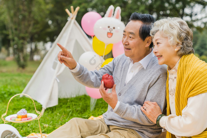 清新老年夫妇吃苹果指向远方摄影图片