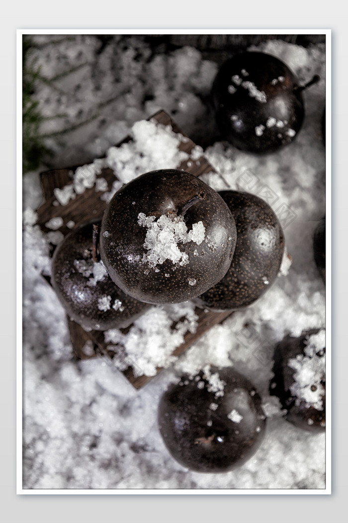黑白色的摄影图 雪地上的冻梨 黑色的梨