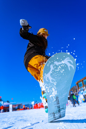 穿着滑雪服的人踩着单板起跳