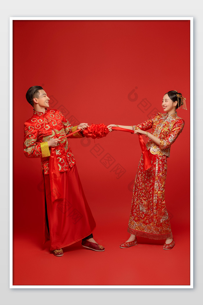穿着中式传统婚服的新人拉扯绣球