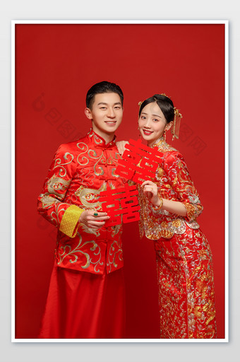 穿着中式传统婚服的新人拿着喜字合影图片