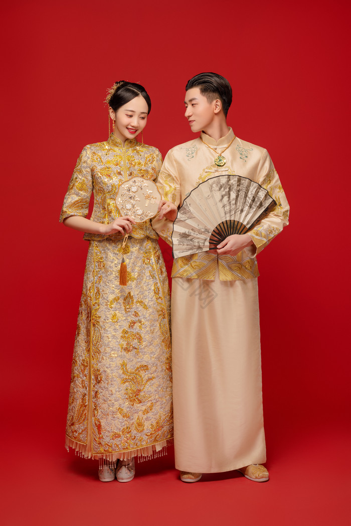 穿着金色传统礼服的新郎看向新娘图片