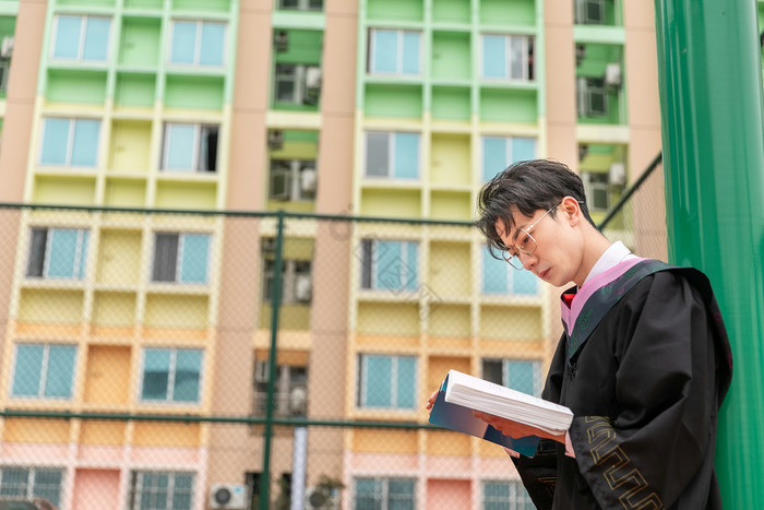 校园生活男大学生背靠球杆看书图片