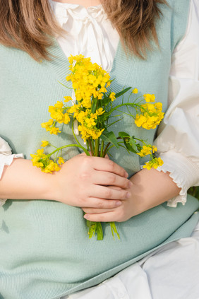 拿着油菜花花枝的少女