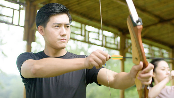 年轻的男子在野外练习射箭实拍