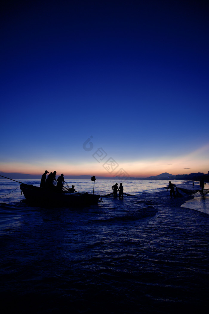傍晚的夕阳海边剪影人像建筑摄影图片