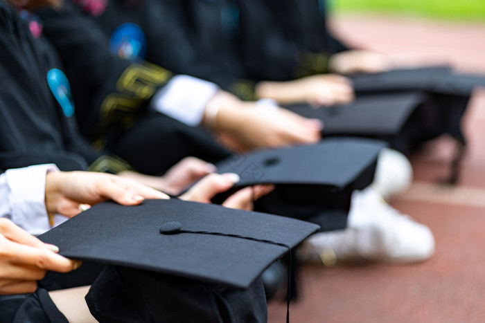 多名大学毕业生拿着学士帽特写图片