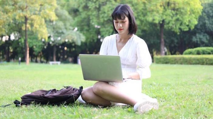草地上玩电脑手机的女性实拍4k