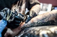 一名纹身艺术家和制造商在皮肤上绘图