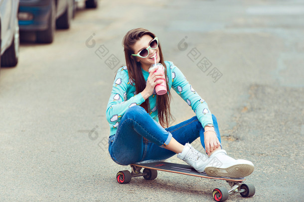 年轻漂亮的女人，和一个滑板，时尚的生活方式，在日落时的合影
