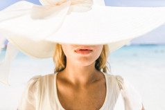 年轻漂亮的女人，戴着帽子在海滩上
