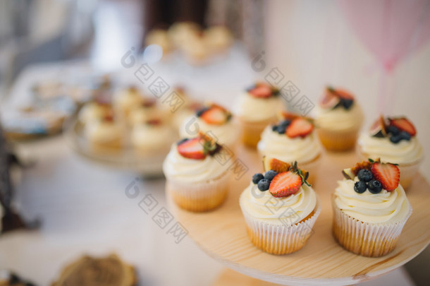 白色奶油蛋糕装饰着草莓和蓝莓的费用，在一个木制的盘子上