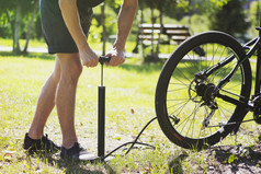 一辆自行车的轮胎充气。自行车修理自行车在森林里。空气注入轮子的自行车。骑自行车的人使用自行车打气筒。空气泵入一个空的轮子的自行车.