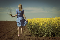 孤独的高加索女人在油菜领域保持流量后视图