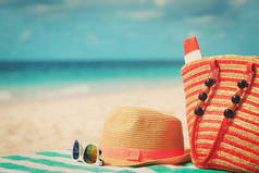帽子，墨镜和防晒霜在海滩上的袋子