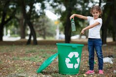垃圾在绿色回收站放上一个模糊的自然背景的小孩。生态污染概念.