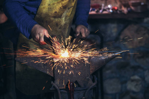 铁匠用火花烟花在铁匠铺的铁砧上手工锻造熔化的金属, 关闭