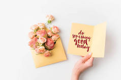 手拿着纸做一些好今天题字旁边粉红色的花朵在信封上隔绝白色