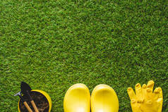 黄色橡胶靴、防护手套和花盆用园艺工具的顶部视图