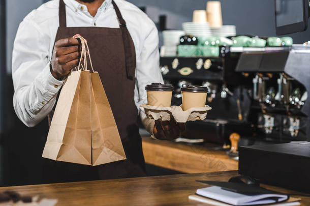 非洲裔美国咖啡师在咖啡馆拿着<strong>一次性</strong>咖啡杯和纸袋的镜头