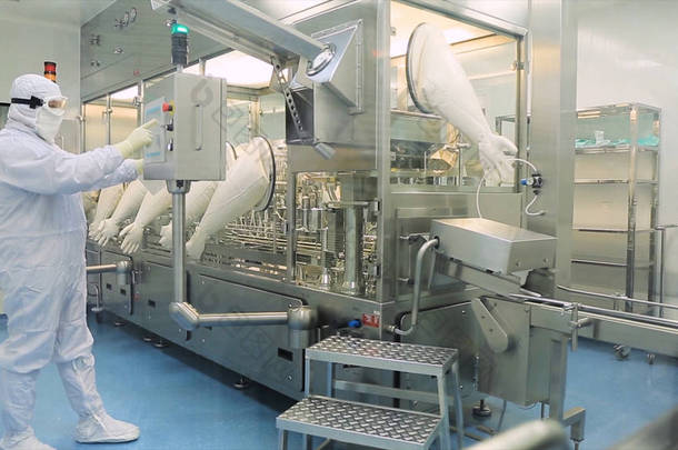 工人在工厂的生产线上的围裙, 帽, 手套与片剂检查过程。质量控制人员在实验室里检查药片. 制药实验室技术员检验质量