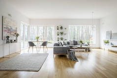 白色典雅起居室内有窗户、灰色角沙发和现代艺术海报