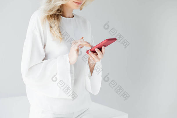在灰色背景下使用智能<strong>手机</strong>在白色服装中裁剪<strong>女性</strong>照片
