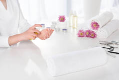 女性在美容沙龙用毛巾、鲜花、蜡烛和指甲用芳香油在餐桌上裁剪图像