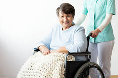 支持坐在轮椅上的快乐残疾老年妇女的护士