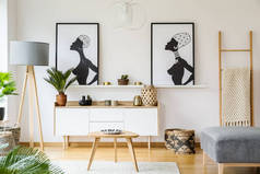 黑色和白色的非洲海报上面的橱柜在客厅内用台灯和桌子。真实照片
