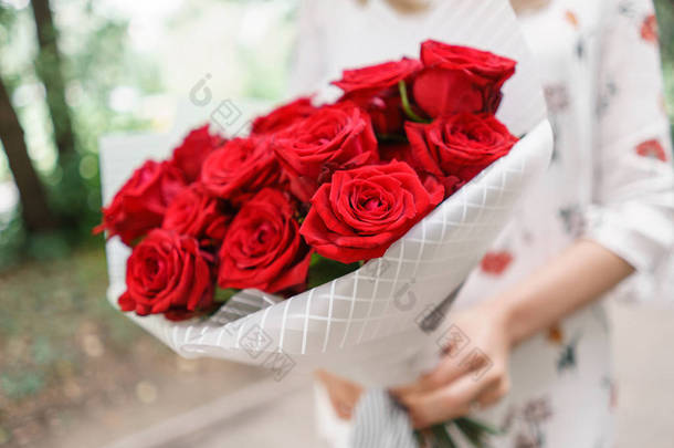美丽的花束。年轻的女孩拿着鲜花安排与<strong>红玫瑰</strong>。<strong>花店</strong>的概念。目录的内容
