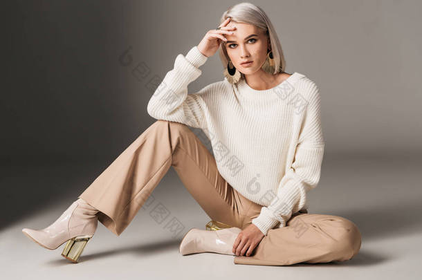 穿着白色新潮毛衣, 米色裤和秋季高跟鞋, 灰色的迷人时尚女人