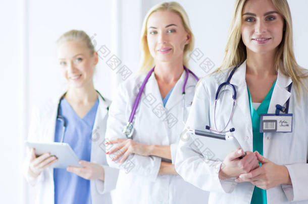站立，双臂交叉在医疗办公室的三名相信女医生的肖像