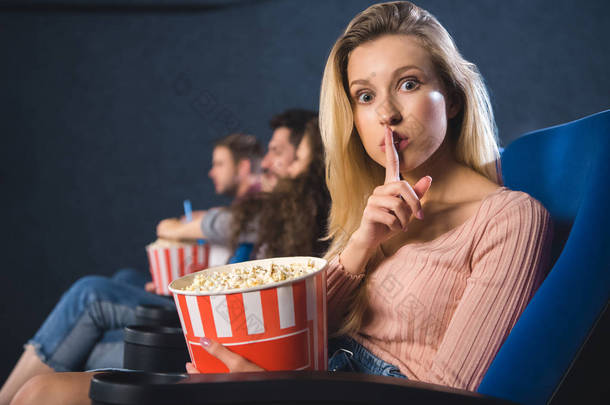 有选择的焦点妇女与爆米花显示沉默标志在电影院