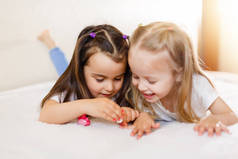 两个小女孩在家里躺在床上画画指甲。.