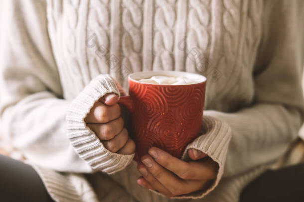 女性手上的毛衣是拿着一杯热咖啡, 巧克力或茶。概念冬天舒适, 早晨饮用, 温暖在冷的中间.