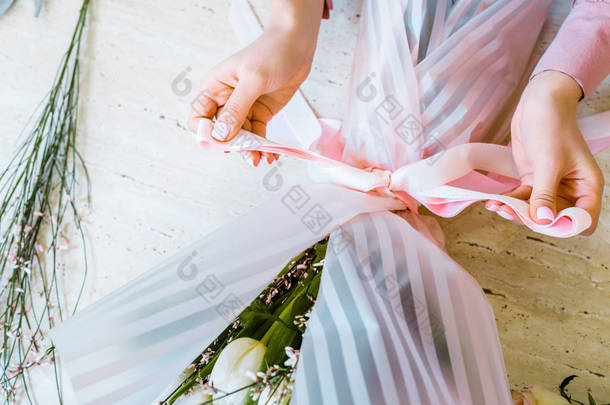 女性花商用丝带绑蝴蝶结的部分观点, 同时包裹花束