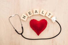 在木制背景上的立方体的顶部看法与健康字母, 玩具心脏和听诊器