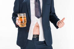 裁剪视图超重男子在正式穿着持有啤酒杯，并显示大拇指隔离在白色