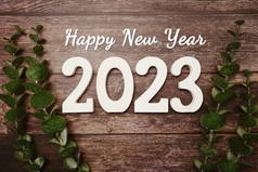新年快乐2023字母表和带有木制背景的复古闹钟