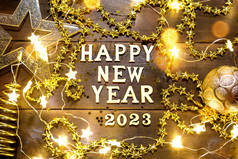 新年快乐-木制信件和数字2023在节日的背景与亮片，星星，闪光，花环灯。问候，明信片。日历，盖住
