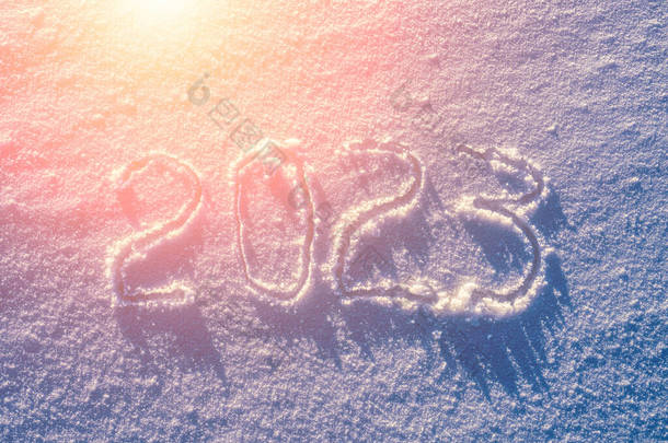 雪地上的数字2023被阳光照亮了。新年和圣诞节的概念.