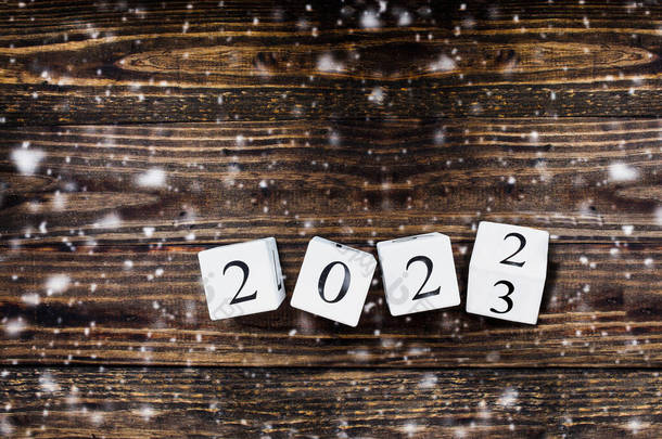 木制的白色日历块<strong>翻动</strong>着2022年至2023年的新年。降雪的桌面视图.