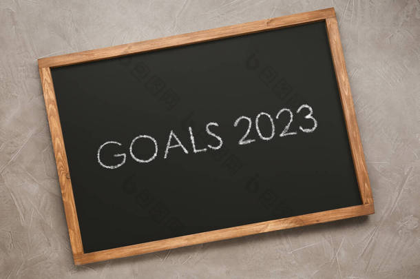 浅灰石质背景，顶部视图的带有短语GOALS <strong>2023</strong>的黑板