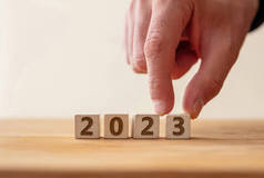 2023新年快乐庆祝理念。2023数字在木制立方体上与手指接触数字3 。新计划，商业，事业，目标，成功。问候语.