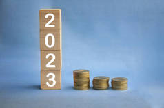 新的2023年，在木块上的文字，蓝色背景的金币。新年概念
