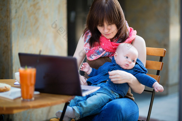 年轻的工作母亲与她的儿子在一家咖啡馆
