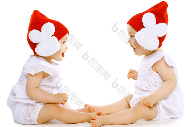 两个有趣的宝贝双胞胎的帽子面对面坐