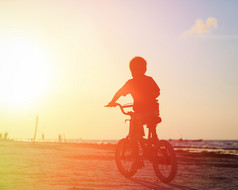 在日落时的小男孩骑自行车