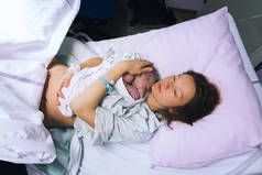 妈妈抱着她刚出生的婴儿在医院分娩后.